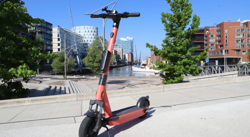 Ein roter E-Scooter in Hamburg, die Elbphilharmonie im Hintergrund.